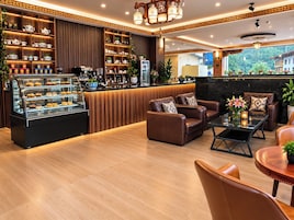 Un área de descanso moderna con sofás de cuero, una estación de café y una vitrina con pasteles.