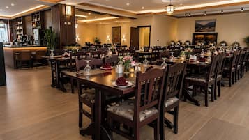 A formal dining area with multiple tables and chairs, a bar area, and a well-lit ceiling with recessed lighting.