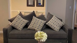 A living room with a dark grey sofa, patterned cushions, a vase with flowers, and a small table. - Classic connection in the Hub City! (Jackson)