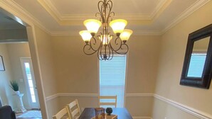 A dining room with a dark wooden table, white chairs, a chandelier, and a patterned rug. - Classic connection in the Hub City! (Jackson)