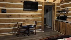 Un interno in legno con un tavolo da pranzo e sedie, una TV a schermo piatto, una decorazione a forma di cuore e un angolo cottura con forno a microonde.