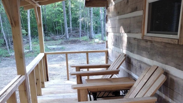 Un terrazzo in legno con panche e una finestra che si affaccia su una zona boschiva.