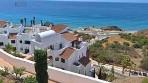 Un bâtiment situé sur la côte, doté d’une façade blanche et d’un toit recouvert de tuiles en terre cuite, qui offre une vue sur la mer.