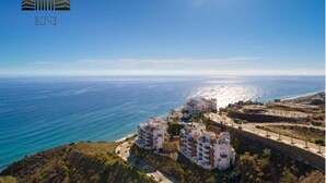 Une vue sur la côte, avec un ciel dégagé, une plage et une zone résidentielle avec des bâtiments.