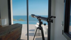 A telescope on a tripod by a glass door with a view of the ocean. - 8 Bedroom Villa in tomino (tomino)