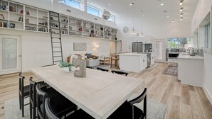 A spacious kitchen with a central island, a dining area with a table and chairs, and a large bookshelf filled with books. - 3-Acre Luxury 5BR Ranch, Movie Theater, 2 Kitchens, Near COTA Airport! Sleeps 14 (Austin)