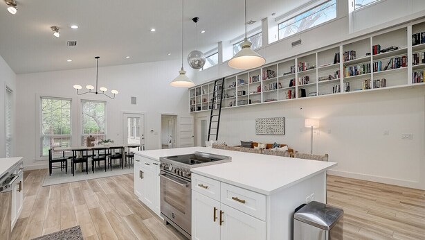 A spacious kitchen with white cabinetry, a central island, and a built-in bookshelf. - 3-Acre Luxury 5BR Ranch, Movie Theater, 2 Kitchens, Near COTA Airport! Sleeps 14 (Austin)