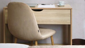 Un espace de travail minimaliste avec un bureau en bois, une chaise beige et une tasse posée sur la table.