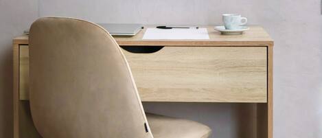 Un espace de travail minimaliste avec un bureau en bois, une chaise beige et une tasse posée sur la table.