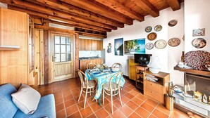 A cozy kitchen with wooden beams, a dining table with chairs, and a blue tablecloth. - Residence Moniga Porto 1-08 by Wonderful Italy (Moniga del Garda)