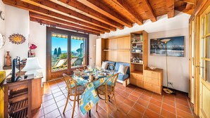 A cozy dining area with a table set for two, wooden chairs, and a view through a door to the outside. - Residence Moniga Porto 1-08 by Wonderful Italy (Moniga del Garda)