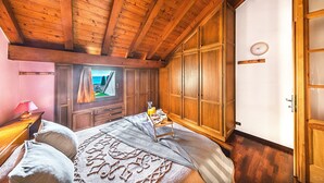 A wooden ceiling, a bed with pillows, a bedside table with a lamp, a window with curtains, and a wardrobe. - Residence Moniga Porto 1-08 by Wonderful Italy (Moniga del Garda)