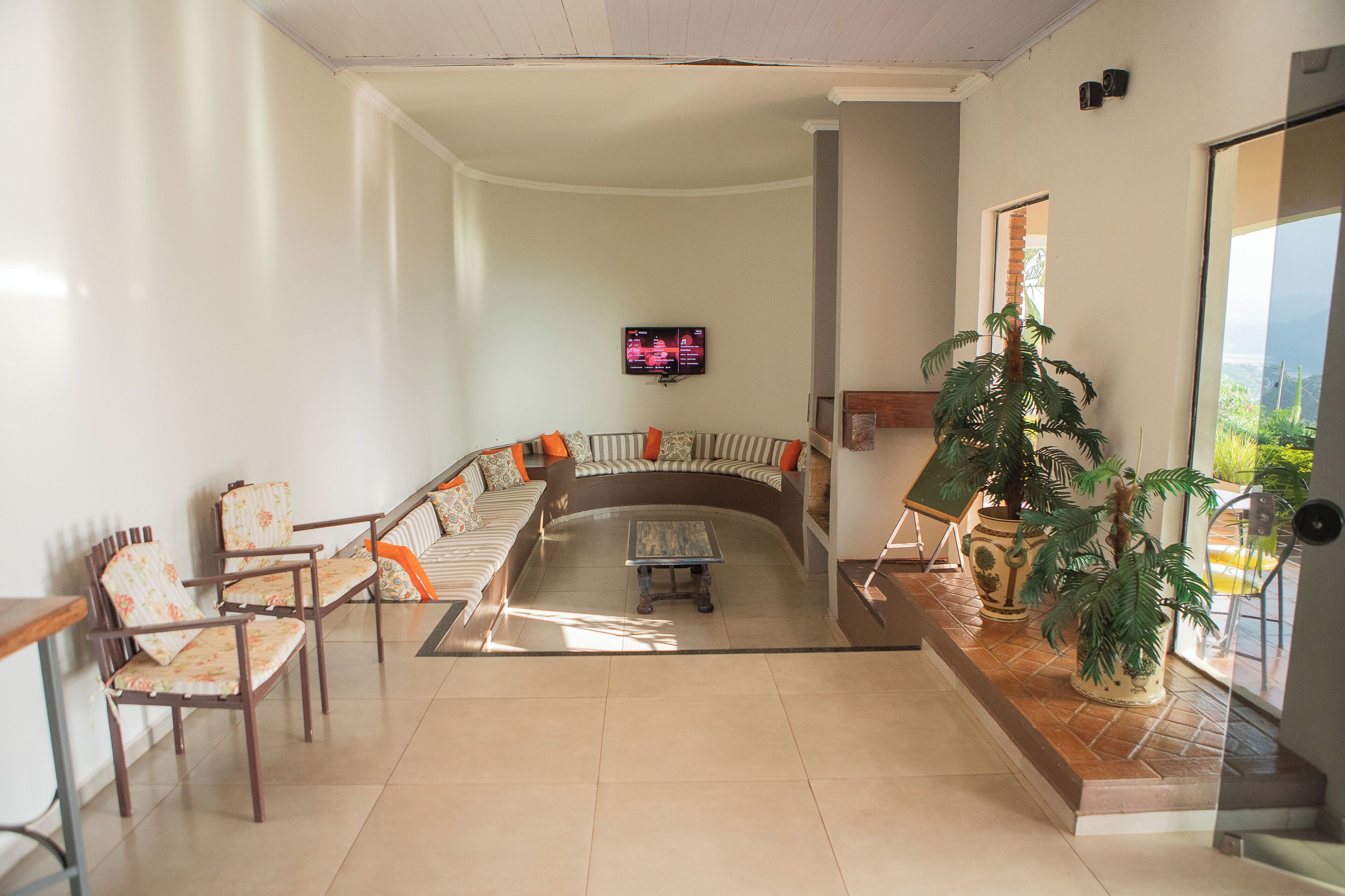Una sala de estar con un sofá curvo, sillas, una mesa de centro y un televisor en la pared.
