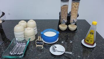 Una encimera de cocina con varios objetos, incluyendo cuencos, un cuenco azul, una cuchara, una botella y un letrero que dice "COALHADA".