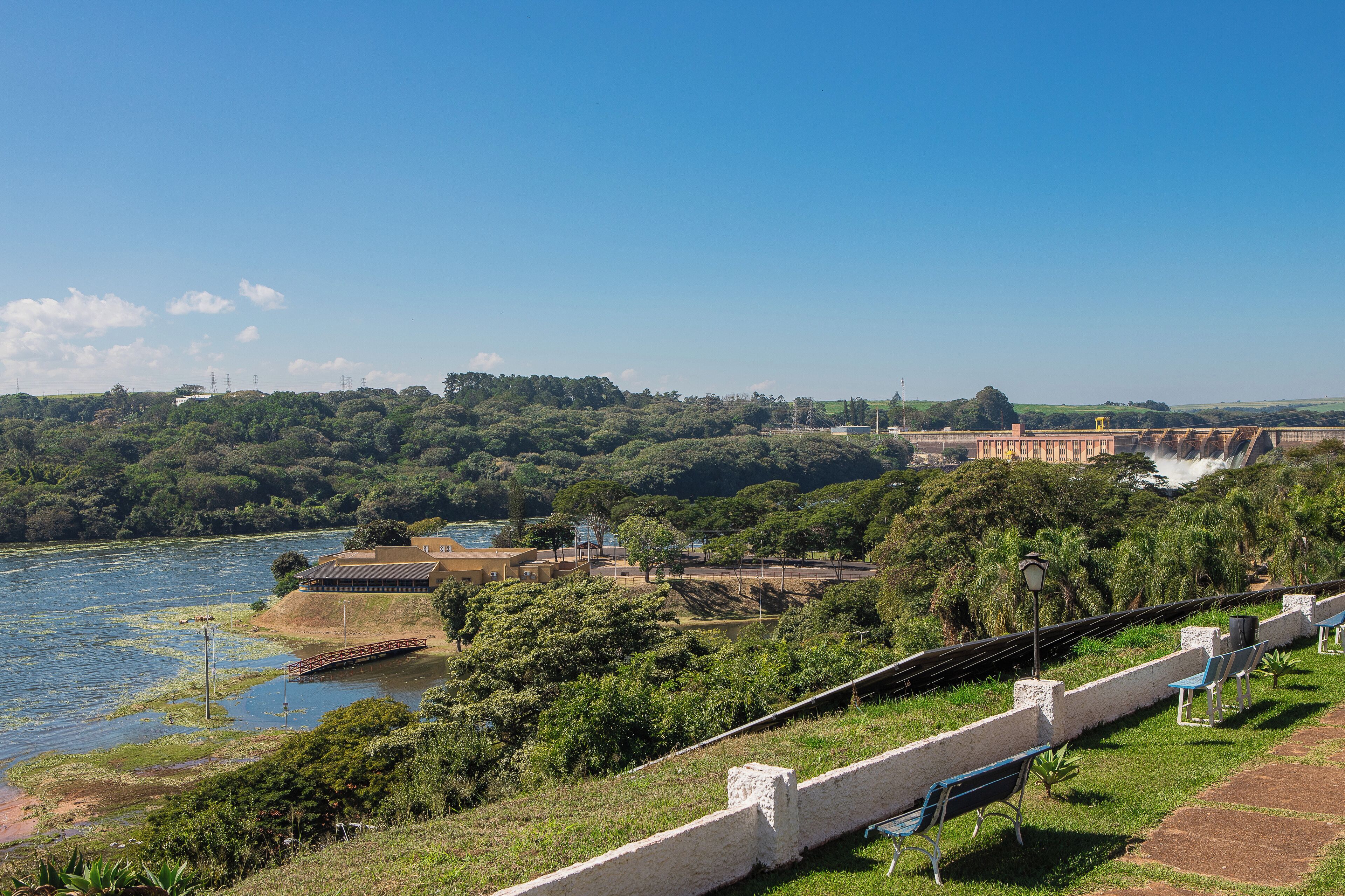 A riverside view with a bridge, greenery, and a building.