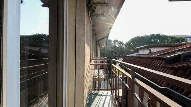 Un balcon avec une balustrade en métal, une vue sur des immeubles et un ciel dégagé.