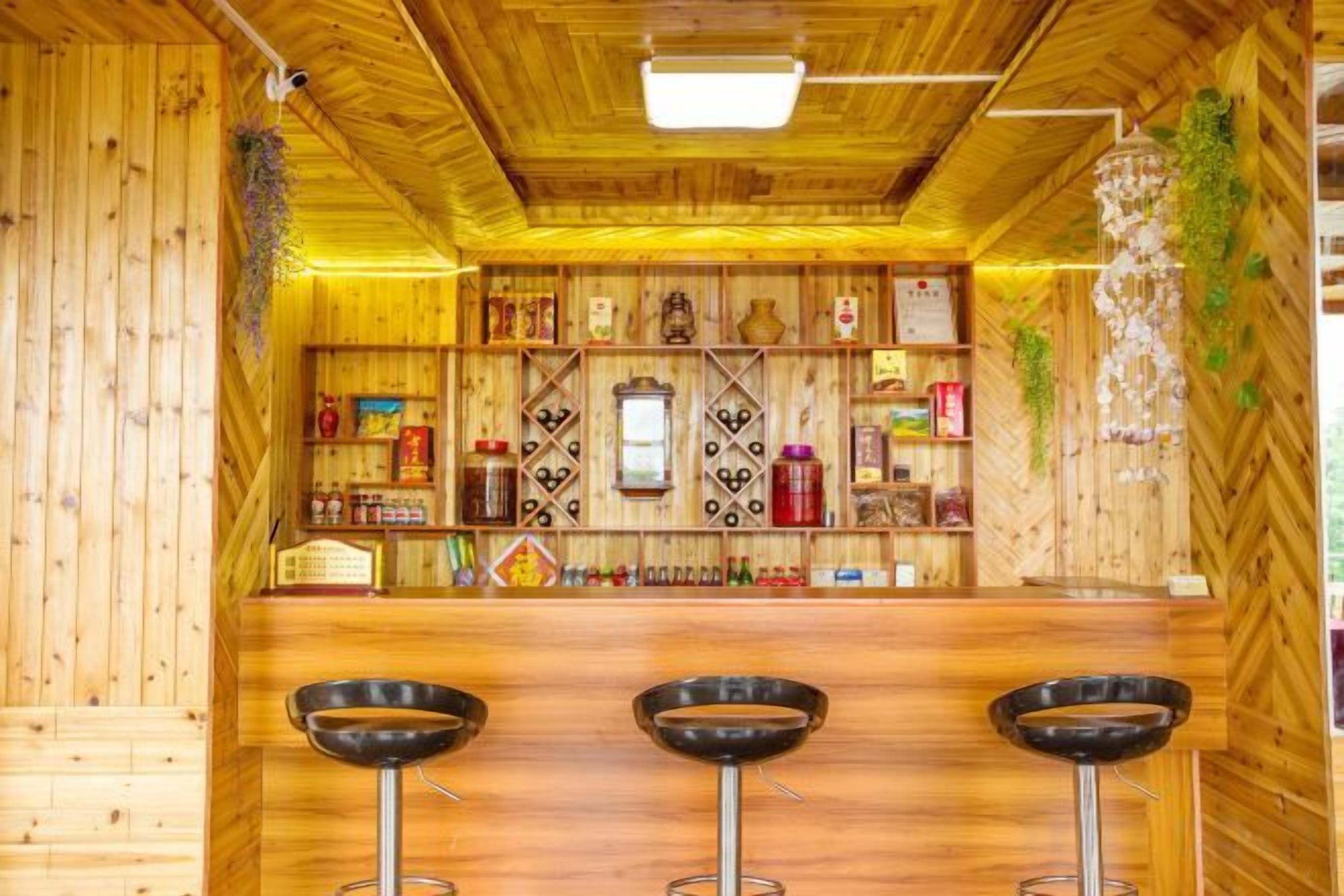 A bar area with wooden walls, a counter, and three stools.