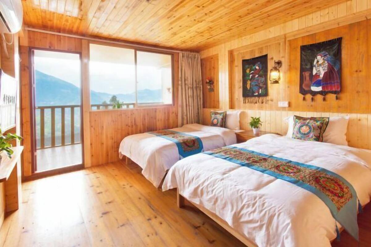 A wooden room with two beds, a balcony, and mountain views.