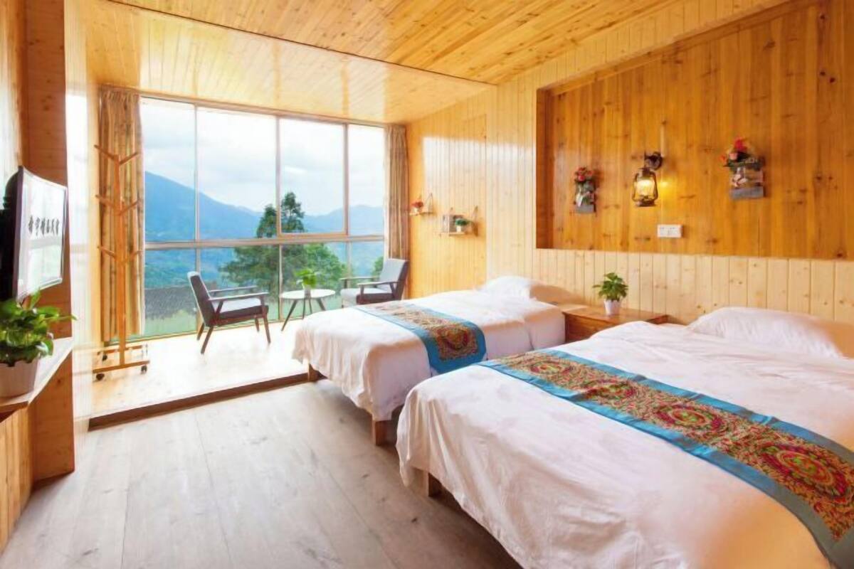 A wooden room with two beds, a desk, and a chair.