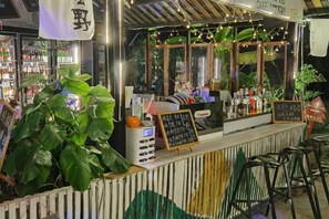 A bar area with a counter, bar stools, and a menu board. - Xiyu Boutique Hostel (Longsheng)