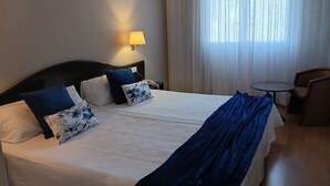 A hotel room with a large bed, two pillows, a bedside lamp, a chair, and a small table. - UTE Hotel Villa de Biar (Biar)
