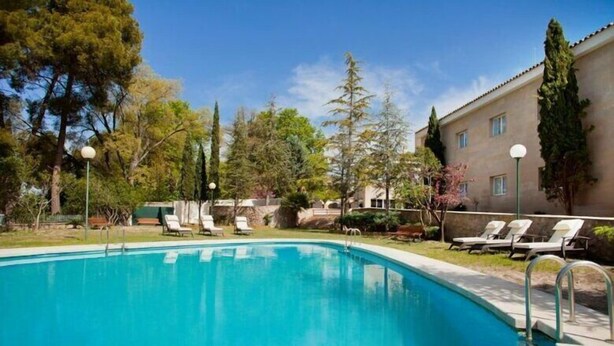 A swimming pool with lounge chairs and a building in the background. - UTE Hotel Villa de Biar (Biar)