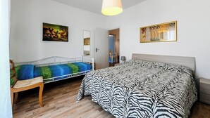 A bedroom with a bed, a chair, and two paintings on the wall. - CAROLINA 7 - Lido di Jesolo, Italy. Entire accommodation (Lido di Jesolo)