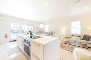 A modern kitchen with a central island, a dining area with a sofa, and a living room with a coffee table.
