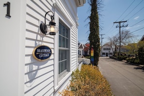 A white building with a sign reading 'Brasswood Cottage.'