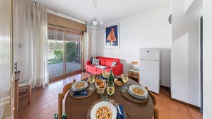 Un comedor con una mesa dispuesta para dos, un sofá rojo y un refrigerador al fondo.