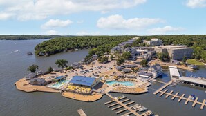 Luchtbeeld van een vakantieoord aan het meer, met meerdere gebouwen, een jachthaven en een groot zwembad.