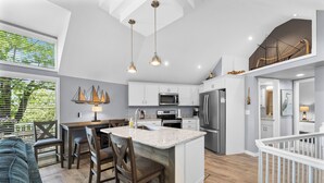 Een moderne keuken met witte kastjes, een centraal eiland en hangende lampen.