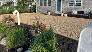 A residential house with a gravel driveway, potted plants, and a front porch area. - Plum Island Beach Cottage - 4 Minute Walk To Beach!! (Newbury)