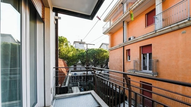 A modern apartment with a balcony, a tiled floor, and a view of neighboring buildings. - Lido di Jesolo, Italy. Entire accommodation (Lido di Jesolo)