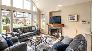 Een woonkamer met een open haard, leren banken, een salontafel en een televisie.
