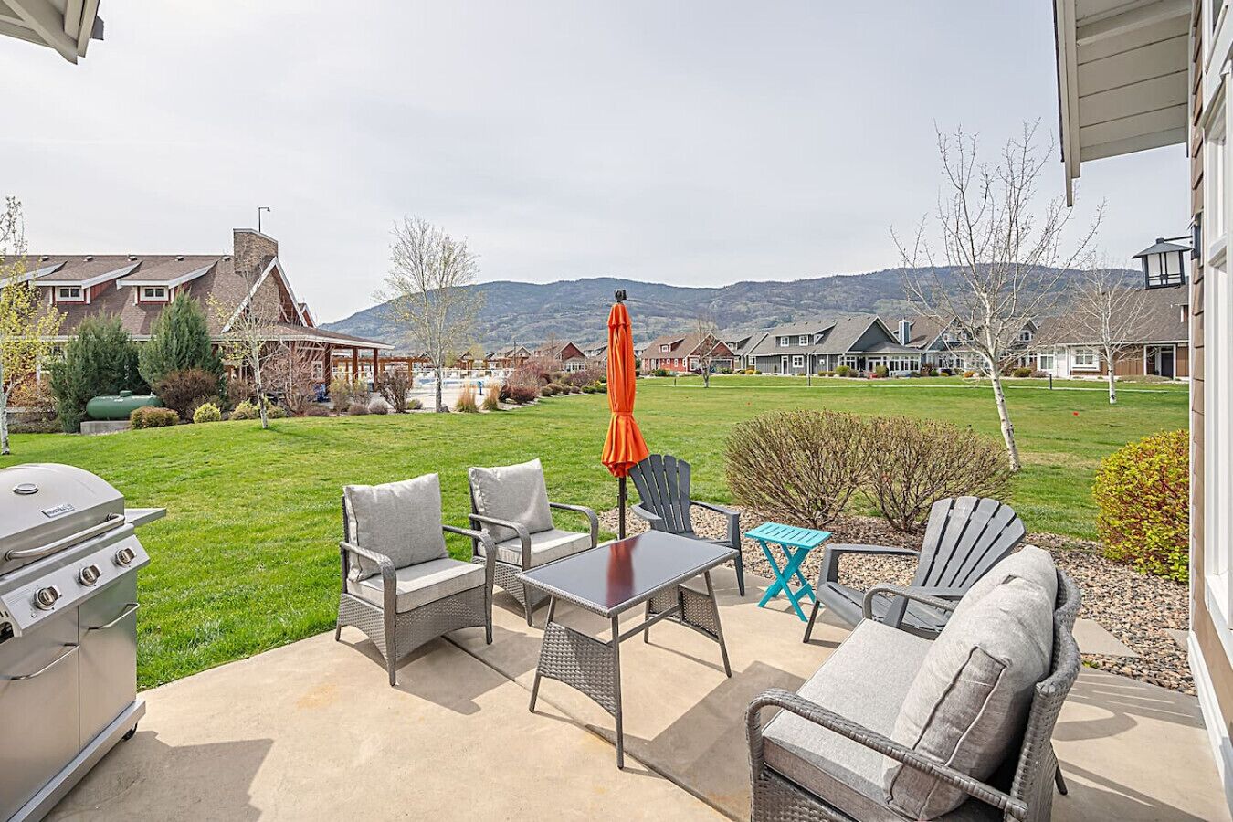 An outdoor patio with a grill, chairs, and a table.