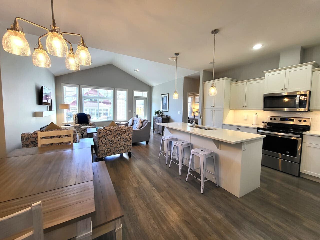 A modern kitchen with white cabinets, stainless steel appliances, and a wooden dining table.