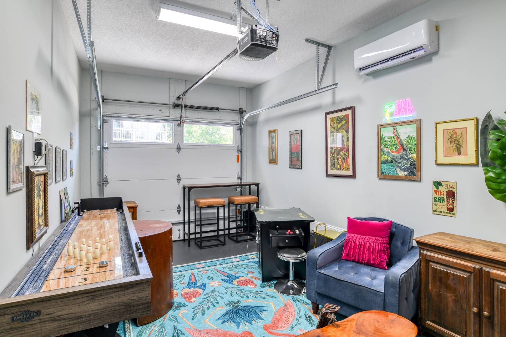Una habitación con mesa de futbolín, zona de bar, sofá azul y mueble de madera.