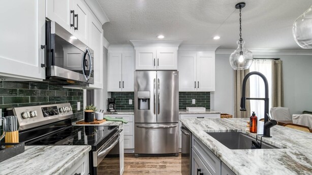A modern kitchen with stainless steel appliances, white cabinets, and a marble countertop. - Lincolnville Nook (St. Augustine)