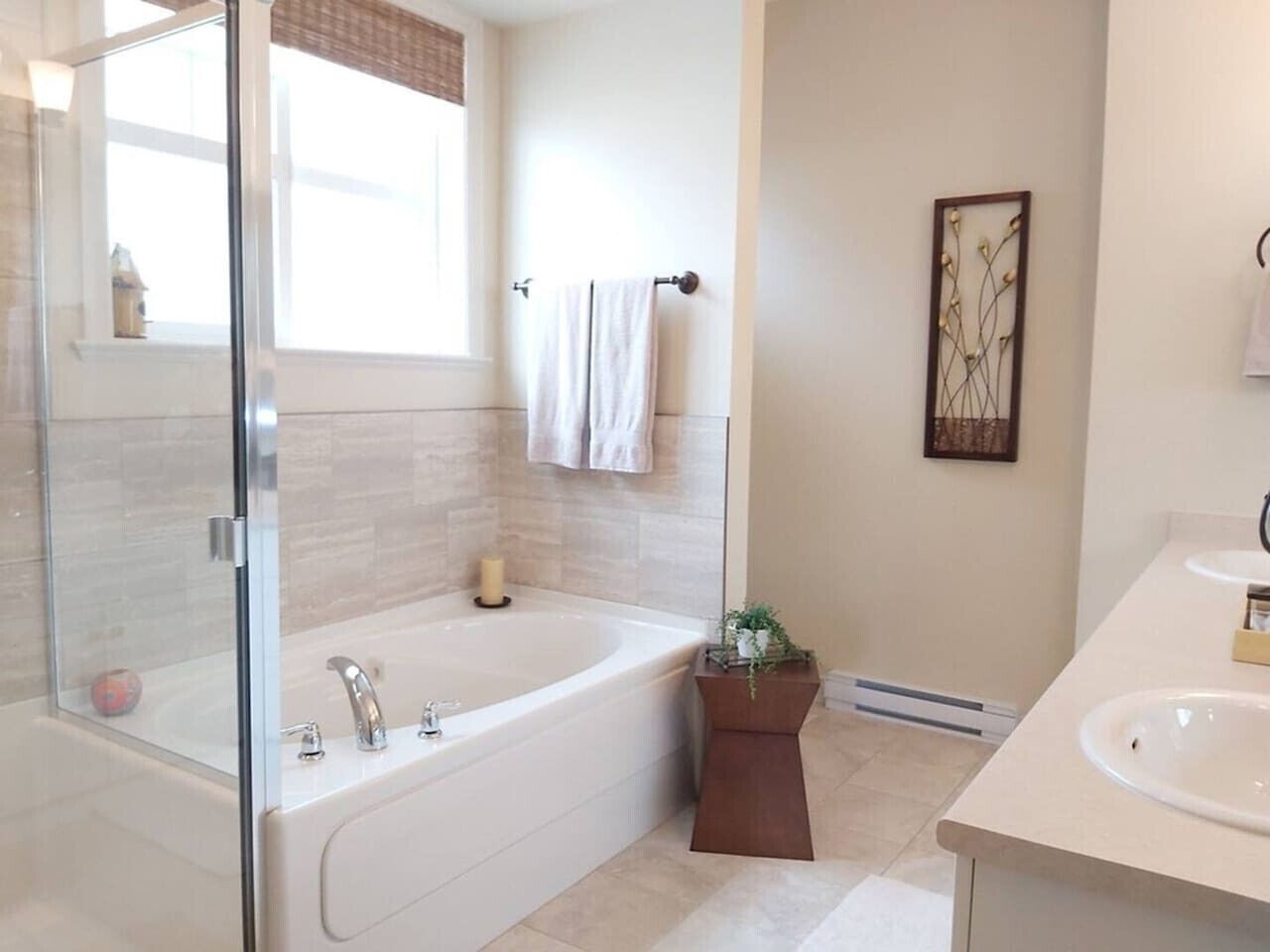 Un baño moderno con ducha envuelta en vidrio, una bañera independiente, tocador con lavamanos y un perchero para toallas.