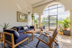 A sunlit patio with a sofa set, a wooden table, and potted plants. - Luxurious Villa with Pool, Close to Sanibel Island (Fort Myers)