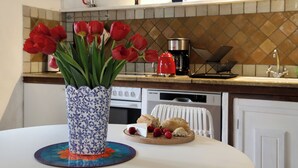 A kitchen with a tiled backsplash, a coffee maker, a toaster, and a vase of red tulips on the counter. - Minori - 2 Bedroom - Private Terrace - Amazing View (Villarzel-Cabardès)