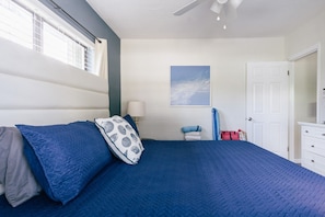 Un dormitorio con cama, mesita de noche, lámpara, ventana y puerta.