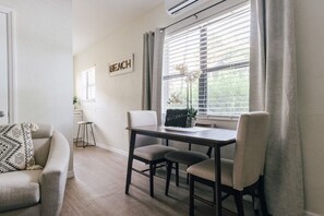 A dining area with a table, chairs, and a window with blinds.