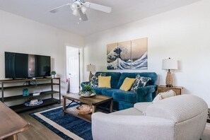 A living room with a sofa, a coffee table, a television, and artwork on the wall.