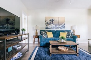 A living room with a blue sofa, wooden coffee table, and a large TV. - One bedroom private apt 2 blocks to beach (Pompano Beach)