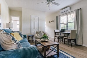 A living room with a sofa, coffee table, and a dining area with chairs and a table. - One bedroom private apt 2 blocks to beach (Pompano Beach)