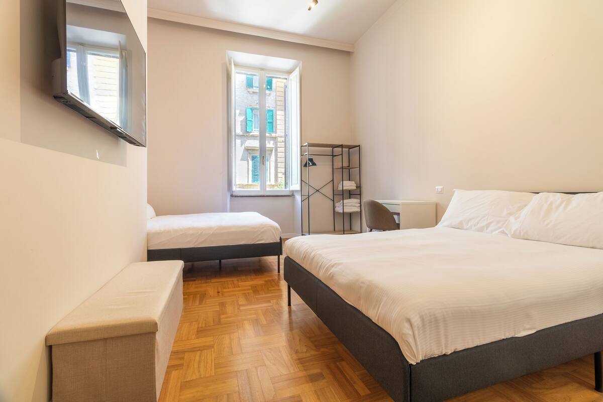 Un dormitorio con una cama grande, una cama más pequeña, un escritorio y una silla.