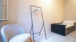 A bedroom with a bed, a chair, and a floor lamp. - Cunabu Emilio (Rome)