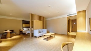 A modern hotel room with a wooden floor, a white sofa, a wooden coffee table, and a wooden desk. - JI Hotel (Shanghai Hongqiao National Exhibition and Convention Center) (Shanghai)